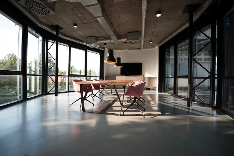 Espaço de trabalho com mesas compartilhadas, monitores e luz natural